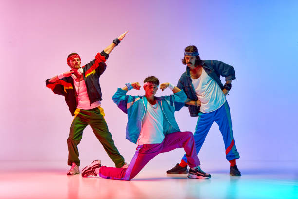 Stylish, handsome three men on old style sportswear training against gradient pink blue background in neon light