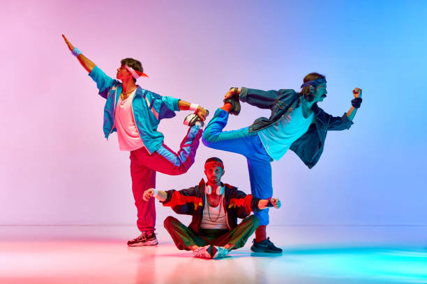istock Funny, athletic young men in vintage sportswear training, doing stretching exercises against gradient pink blue background in neon light 1746441101