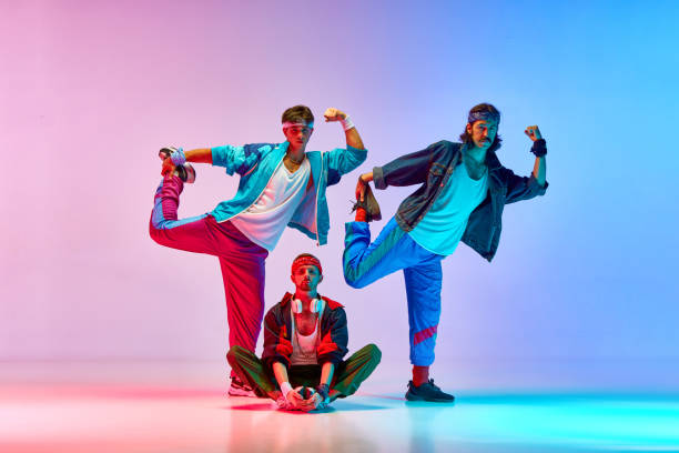 istock Funny, athletic young men in vintage sportswear training, doing stretching exercises against gradient pink blue background in neon light 1746441103