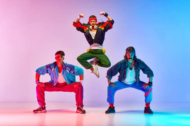 istock Team. Friends, tree men in colorful retro sportswear standing in pyramid pose against gradient pink blue background in neon light 1746441106