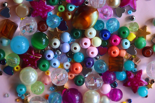 Various colorful beads on bright pink background. Top view.