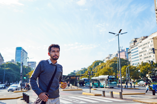 portrait young latin american businessman walking down the street through the city center