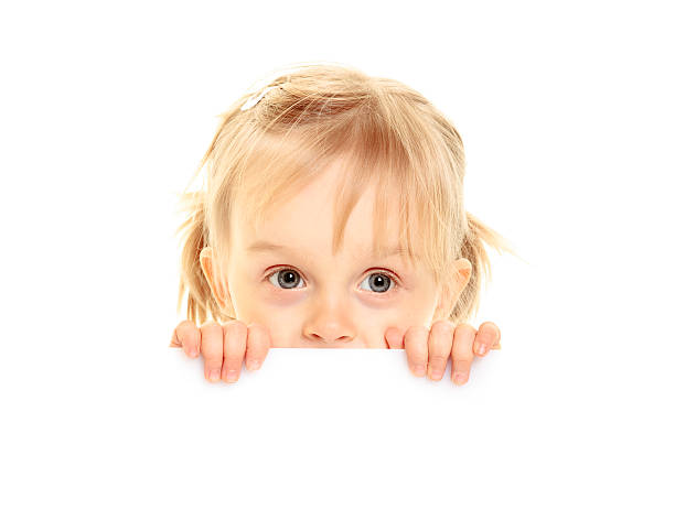 Sad little girl peeking from behind the advert. stock photo