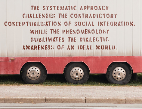 Complex philosophical thoughts stenciled on the side of a parked truck. The text was digitally superimposed and a release is provided