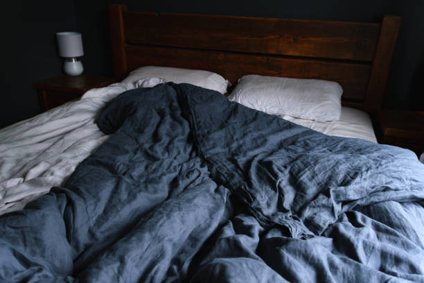 istock cosy Interior with white bed linen. Bedroom with oak bed, grey and blue bedding, and bedside table 1746479085
