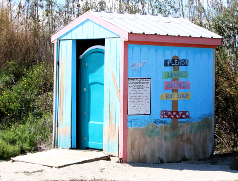 a painted house around a port-a-potty on a Texas beach