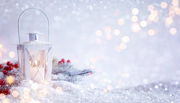 Christmas lantern with fir tree branch and holly berries on snowy table