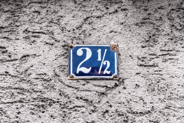 House address - number 2 an a half on a blue enamel sign. White housewall in the background. Bavaria, Germany.