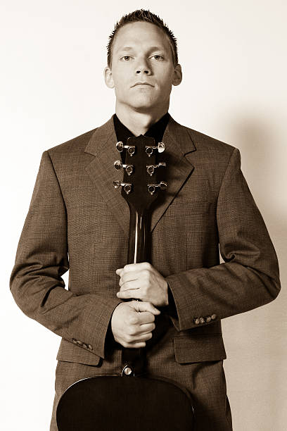 A handsome musician with guitar in a serious pose.