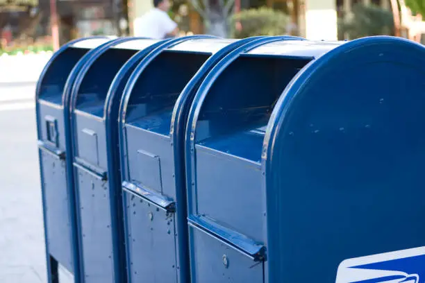 Photo of Four bright blue USPS mailboxes in a row