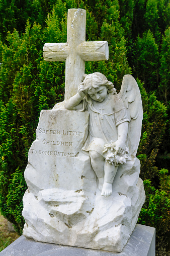 Statue of an angel beside a cross with the inscription 