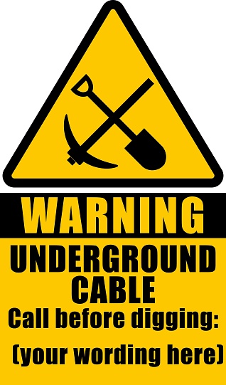 Warning, underground cable. Call before digging. Yellow hazard sign with pick and shovel silhouettes. Text below.