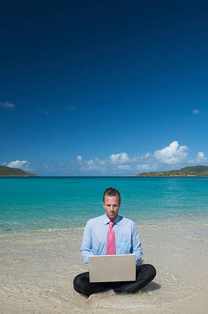 istock Businessman Sits at Tropical Beach Working on Laptop in Waves 174653410