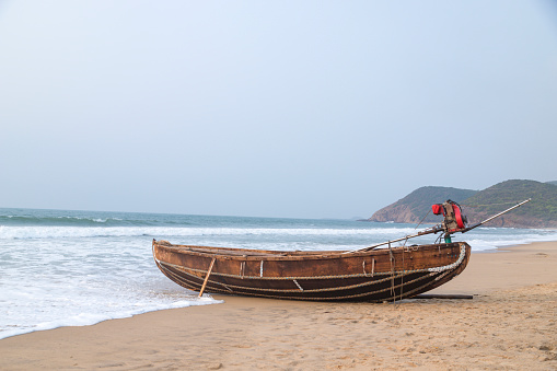 A fisherman boat against the on gushing sea waves at the beach at visakhapatnam, andhra pradesh, India at sunset time.