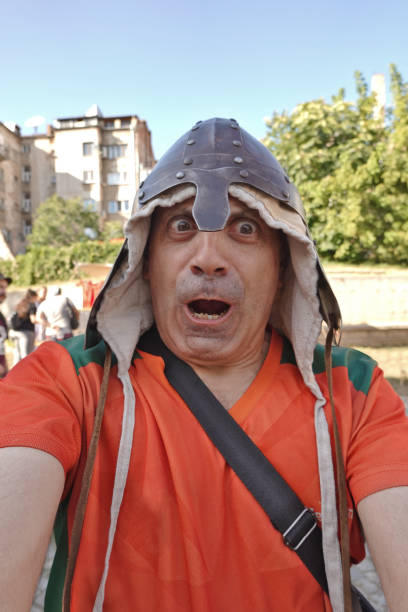 Selfie of a man with a knight's helmet on his head taken with his smartphone during medieval battle reenactment.