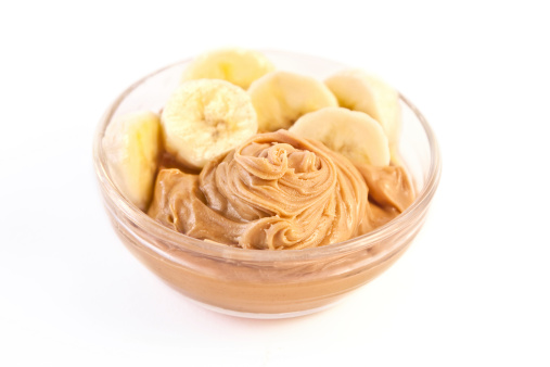 Bowl of peanut butter and bananas on white background - shallow depth of field.[/url]