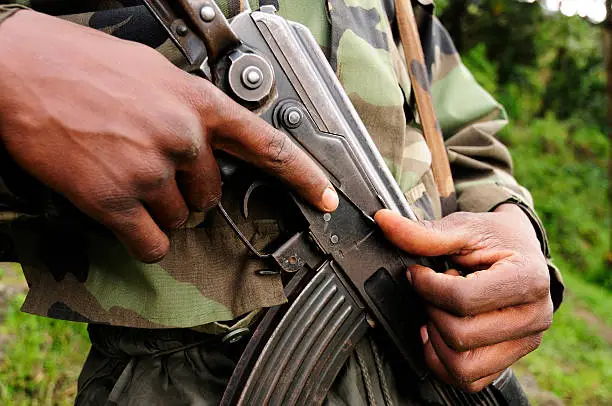 An African soldier grips a Kalashnikov type semi-automatic assault rifle.