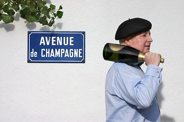 Man with Champagne passing sign saying Avenue de Champagne At the heart of the Champagne region is Epernay, with it’s Avenue of Champagne. An avenue that contains 9 famous Champagne Houses, of which the the largest has 17 miles of underground caves and storage of 100 million bottles. Epernay is truly the the 'Capital of Champagne' campania photos stock pictures, royalty-free photos & images
