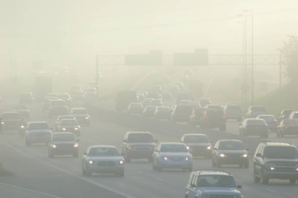 autos in der hauptverkehrszeit fahren zwischen dicken smog - luftverschmutzung stock-fotos und bilder