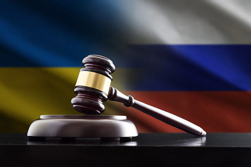 Concept of political agreements and negotiations between Ukraine and Russia with judge's gavel on black wooden table and flags in the background.