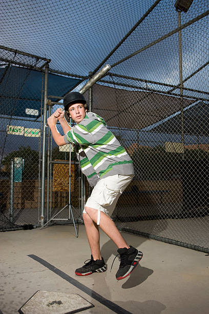 Teen in Batting Cage Teen in Batting Cage baseball cage stock pictures, royalty-free photos & images