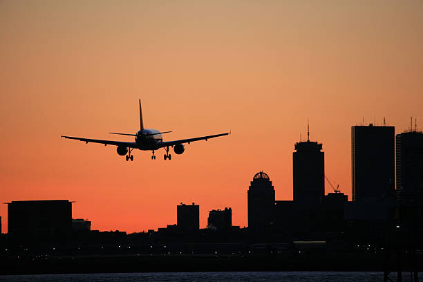 Boston Skyline Logan Airport Arrival Airliner Sunset A large airliner lands at Boston's Logan International Airport. Boston skyline and sunset sky. prudential tower stock pictures, royalty-free photos & images