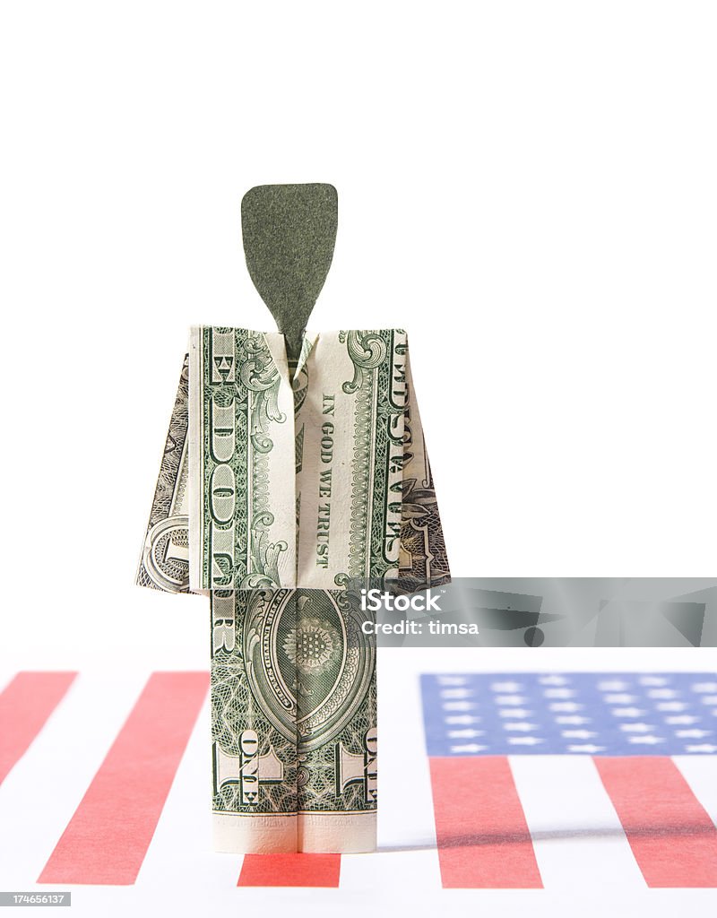 Dollar person on American Flag Suited person folded out of an American dollar standing atop a pale American Flag. Folded Stock Photo