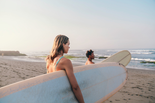 young couple preparing to go surfing at dawn