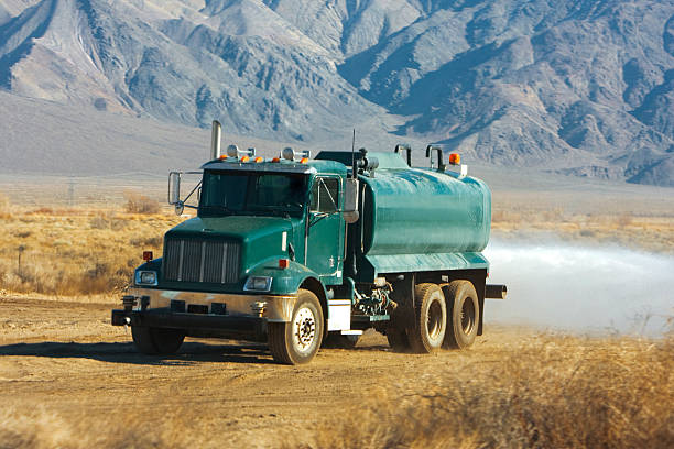 A water truck sprays water at a construction site.