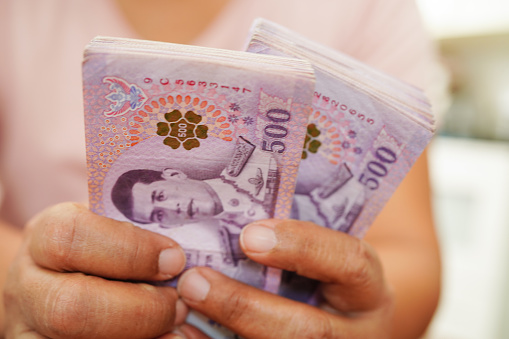 Mujer asiática contando el dinero de los billetes de baht tailandeses y sosteniéndolo en la mano, economía de inversión, negocios de contabilidad y banca. photo