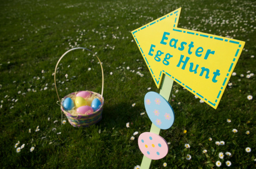 SIgn for Easter Egg Hunt points to a basket in a flowery meadow
