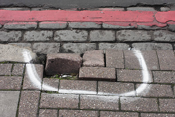 Broken pavement damaged sidewalk kerb raised bricks marked for repair