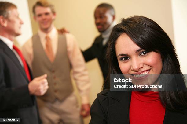 Foto de Feliz Mulher Hispânica No Escritório Com Os Trabalhadores Em Fundo e mais fotos de stock de Negócios