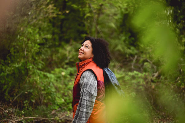 American woman with backpack enjoying hiking in forest.