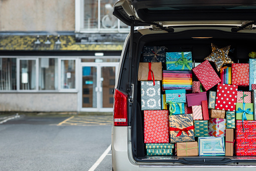 A wide shot of a van trunk filled with wrapped Christmas gifts.
