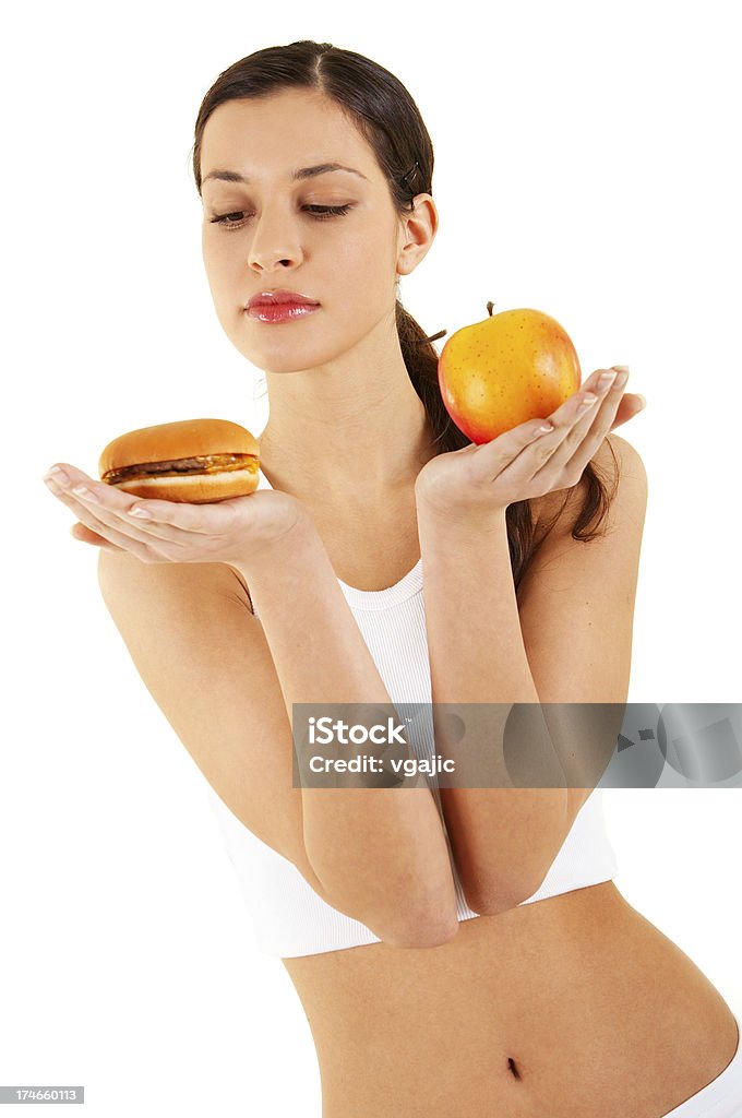 Woman holding apple and hamburger Young beautiful woman choosing between hamburger and apple Adult Stock Photo