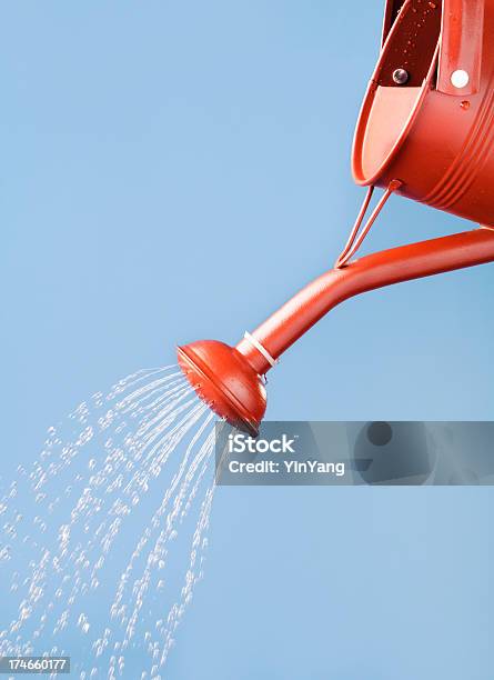 Red Watering Can Pouring Sprinkling Flowing Water Against Blue Sky Stock Photo - Download Image Now