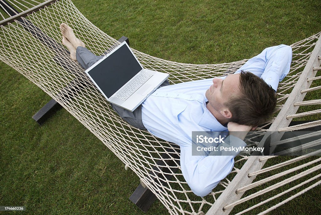 Uomo d'affari prendendo con portatile relax sull'amaca - Foto stock royalty-free di Amaca