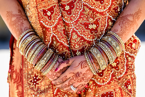 Indian bride's closeup of hands with mehndi/henna, bangles, rings and Indian wedding dress  just before the marriage ceremony.