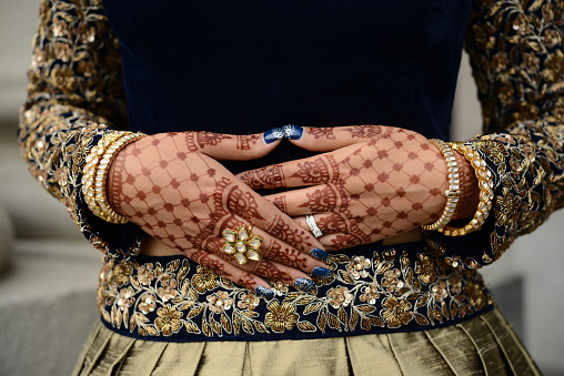 Indian brides closeup of hands with mehndi/henna, bangles, rings and Indian wedding dress  just before the marriage ceremony.