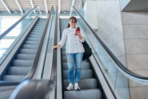 istock Middle-aged woman with backpack in casual style on escalator 1746604211