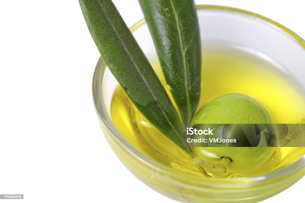 Green olive in oil Lovely fresh green olive immersed in olive oil with foliage still attached. Bowl Stock Photo