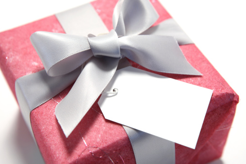 Close-up of a silver ribbon gift with blank gift tag.