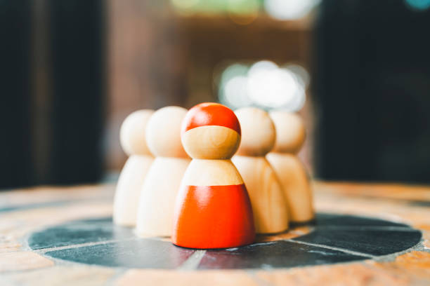 A red wooden figure standing with a team to influence and empowerment. Concept of leadership, successful competition winner and Leader with influence and Social distancing for a new normal lifestyle. stock photo
