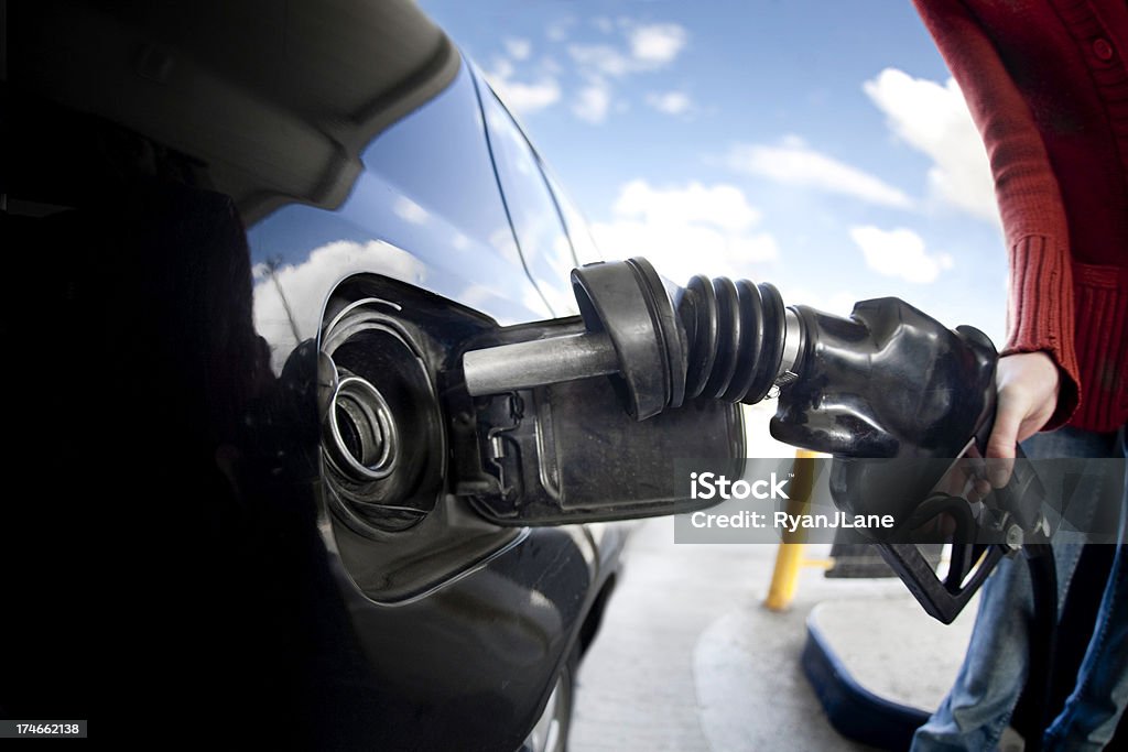 Pumping At The Gas Station A wide angle shot of a gas pump nozzle being inserted into the gas tank, held by a woman's hand.  Lot's of copy space. Car Stock Photo