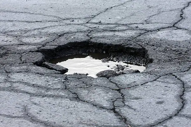 "Broken asphalt pavement resulting in a pothole, dangerous to motorists. Shot with shallow dof.  ....recent addition"