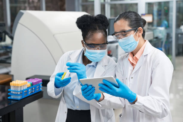 istock Female scientists wearing protective face masks while discussing over digital tablet at laboratory 1746635178