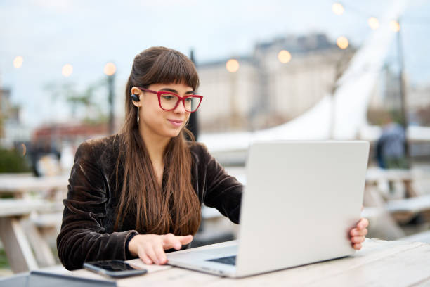 istock woman sitting and using laptop outdoors 1746640193