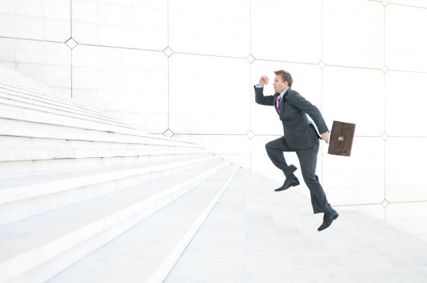 istock Businessman Runs Up Long White Staircase 174664319