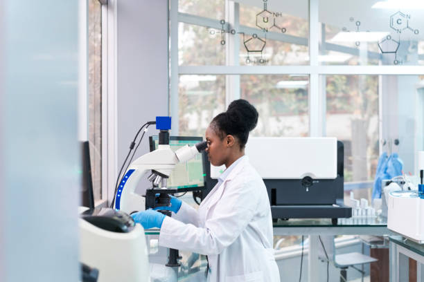 istock Side view of young female scientist looking through microscope at laboratory 1746645004